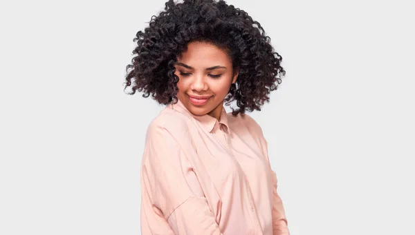 Mujer de piel oscura soñadora sonriendo ampliamente con los ojos cerrados, vistiendo camisa beige, disfrutar del buen tiempo, posando contra la pared blanca del estudio. Gente, éxito, emociones y concepto de felicidad — Foto de Stock