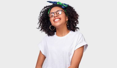 Güzel rüya gibi esmer genç kadın mutlu hissediyor ve havanın tadını beyaz t-shirt giymiş. Geniş gülümseyerek, yuvarlak beyaz stüdyo duvardan poz gözlük takan Afrikalı-Amerikalı kadın