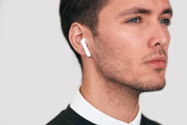 Portre studio ciddi genç yakışıklı adam beyaz stüdyo arka planda radyo earphones ile poz portresi. Kablosuz Kulaklık kullanarak beyaz iş adamı. İnsanlar, teknoloji ve iş kavramı