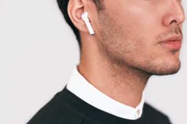 Beyaz stüdyo arka planda radyo earphones ile poz ciddi genç yakışıklı bir adam portresi closeup kırpılmış. Kablosuz Kulaklık kullanarak beyaz iş adamı. İnsanlar, teknoloji ve iş kavramı
