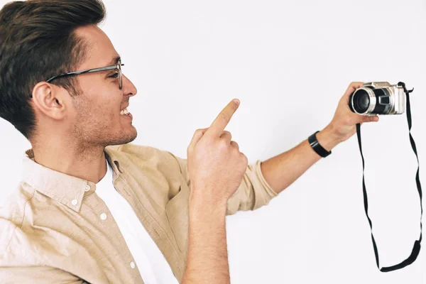 Homme freelance joyeux prenant selfie sur fond blanc studio. Jeune homme souriant et portant des lunettes faisant l'autoportrait et bloguant en utilisant un appareil photo numérique . — Photo