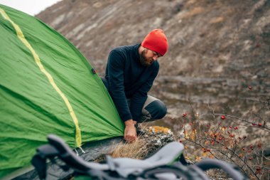 Gezgin sakallı erkek sırt çantasını dağcılık için hazırlanıyor. Seyahat sırt çantası ile dağlarda hiking genç uzun yürüyüşe çıkan kimse adam görüntüsü. Seyahat, insanlar ve sağlıklı yaşam konsepti