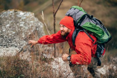 Yeni yerler keşfetmek kırmızı elbiseler giyinmiş aşırı genç uzun yürüyüşe çıkan kimse adam dağlarda hiking. Gezgin erkek trekking ve dağcılık yaptığı yolculuk sırasında sakallı. Seyahat, insanlar, spor, yaşam kavramı