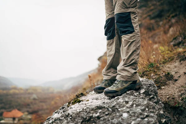 Ao ar livre cortado de perto imagem de pernas de homem jovem caminhadas nas montanhas. Pés de homem viajante em pé na rocha durante o trekking. Viagens, pessoas e conceito de estilo de vida saudável — Fotografia de Stock