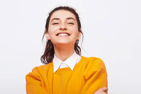 Estúdio tiro de encantadora jovem, sorri amplamente, veste camisola laranja com camisa branca. Menina estudante muito positiva se sente alegre posando sobre a parede do estúdio branco. Pessoas e emoções — Fotografia de Stock