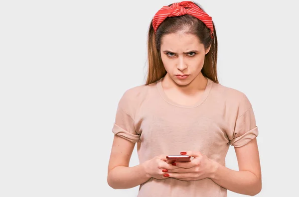 Indoor portrait of sad young atrractive female holding mobile phone in her hands reading message from her boyfriend. Young woman student learning with smart phone online using free wireless — Stock Photo, Image