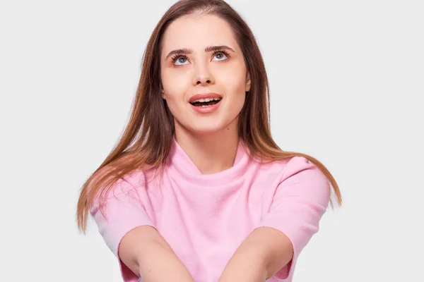 Pretty Caucasian woman student wearing pink blouse, smiling broadly, looking up with amazed expression, isolated over white background. — Stock Photo, Image