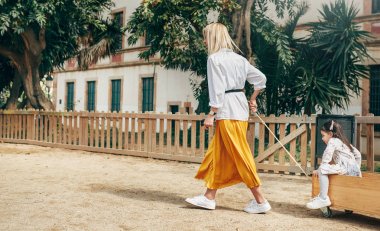 Güzel mutlu genç sarışın anne oyun alanında onu sevimli kızı ile oynarken Yatay görüntü. Samimi bir kadın dışarıda yeni yürümeye başlayan çocuğuyla oynuyor. Annelik ve çocukluk. Anneler günü