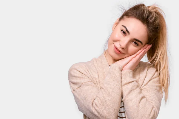 Kind young woman in beige sweater and ponytail, smiling with pleasant expression, looking to the camera, isolated over white background. People emotions — Stock Photo, Image