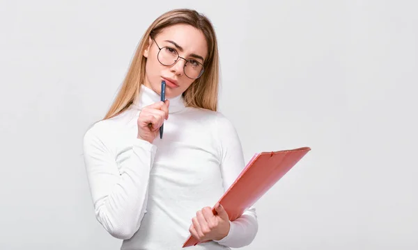 Imagem interior de uma jovem empresária séria vestindo blusa branca e óculos redondos da moda com pasta vermelha na mão, com espaço em branco para o seu texto . — Fotografia de Stock