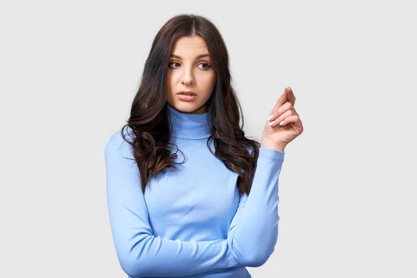 Studio wizerunek poważnej młodej kobiety, nosi niebieską bluzkę z długim rękawem, patrząc na bok. Kaukaski brunetka Kobieta w niebieskiej bluzki stwarzające nad białym Studio ścianie. Koncepcja ludzi i emocji — Zdjęcie stockowe