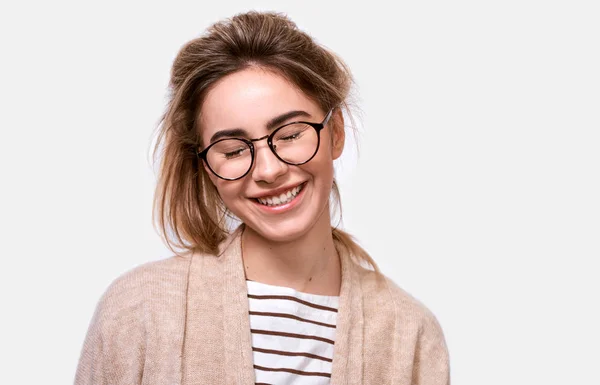 Horizontal close up retrato de mulher positiva sonhadora em roupa casual e óculos, sorrindo com os olhos fechados, imagina algo agradável, posando sobre fundo branco. Pessoas emoções positivas — Fotografia de Stock