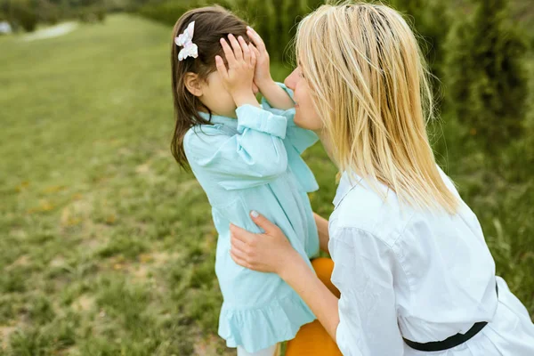 Ładne dziecko gra ukryć i szukać z młodą matką na zewnątrz. Portret radosnej kobiety i jej cute dziecko bawią się w parku. Matka i córka akcji miłości. Szczęśliwego dnia matki. Macierzyństwo, dzieciństwo — Zdjęcie stockowe