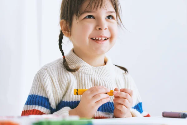 Feliz linda niña pintura con lápices de colores, sentado en el escritorio blanco en casa. Dibujo infantil alegre con lápices. Concepto de personas, infancia y educación — Foto de Stock