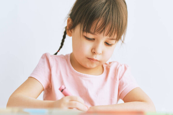Creative little girl drawing with colorful pencils. Cute child learning to wrtite on paper at the desk, at kindergarten. People, childhood, education