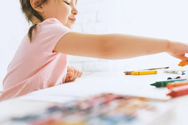 Gadis seniman kecil menggambar dengan pensil berwarna-warni, mengenakan kaos merah muda. Anak TK yang lucu melukis dan belajar di taman kanak-kanak. Orang-orang, masa kecil, pendidikan — Stok Foto