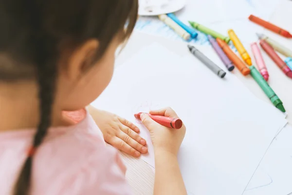 Citra tampilan belakang gadis kecil yang lucu menggambar dengan pensil berwarna-warni, mengenakan t-shirt merah muda. Pretty prasekolah anak lukisan dan belajar di taman kanak-kanak. Orang-orang, masa kecil, pendidikan — Stok Foto