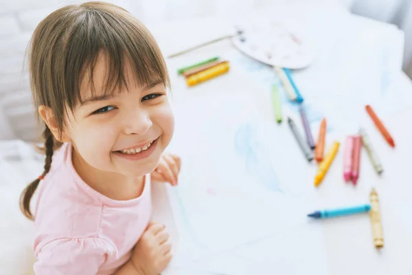 Portré boldog kislány mosolygott és rajz színes ceruza, öltözött rózsaszín póló. Szép preschooler gyermek festészet és a tanulás az óvodában. Emberek, gyermekkor, oktatás — Stock Fotó