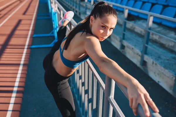 Fitness jeune femme s'étirant avant le jogging au stade. Athlétique femelle étirement après l'entraînement en plein air. Concept du sport et des personnes — Photo