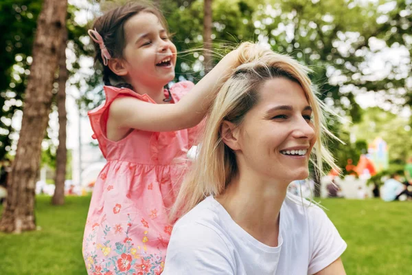 Primer plano retrato al aire libre de un niño feliz jugando con la madre en el parque. Mujer alegre y su lindo hijo jugando afuera. Mamá y la niña comparten el amor. Feliz Día de las Madres. Maternidad e infancia — Foto de Stock