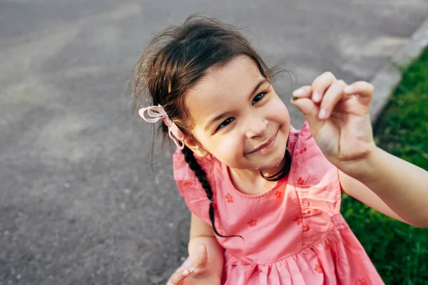 Εξωτερική εικόνα του χαριτωμένο ευτυχισμένο παιδί χαμογελά και ψάχνει να έντομο στα δάχτυλά της στο πάρκο της πόλης. Όμορφο μικρό κορίτσι παίζοντας και εξερευνώντας τη ζωή της φύσης στις καλοκαιρινές διακοπές. — Φωτογραφία Αρχείου