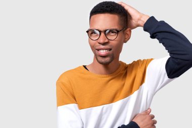 Düşünceli Afrikalı adam gülümseyerek başını el tutarak ve boş kopya alanı bakıyor. Emin yüz düşünme ve karar beyaz stüdyo arka plan izole verme ile şüpheli koyu tenli erkek