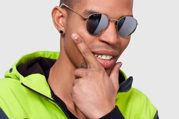 Gros plan portrait studio d'homme afro-américain souriant et posant pour la publicité portant des lunettes de soleil miroir à la mode, isolé sur un mur blanc avec de l'espace de copie pour votre texte. Personnes, émotions, mode de vie — Photo