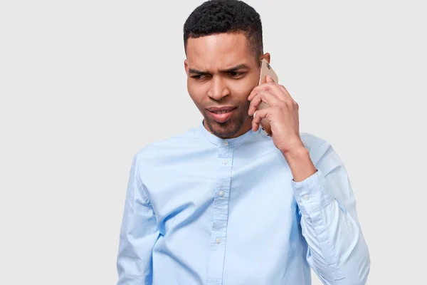 真面目なアフリカ系アメリカ人の若者がスマートフォンで話している。動揺アフロの男性は、彼のガールフレンドと会話を持っています。人と技術の概念 — ストック写真