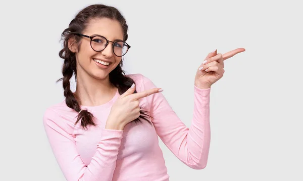 Wewnętrzny wizerunek szczęśliwej młodej kobiety brunetka w przezroczystych okularach, wskazuje na bok z palcami do pustej kopii miejsca dla Ciebie tekst promocyjny, izolowane na białym ścianie. — Zdjęcie stockowe
