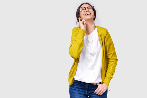 Студия горизонтального снимка красивой белой молодой женщины, широко улыбающейся, слушающей музыку в наушниках. Счастливая женщина наслаждается любимыми песнями в наушниках. Люди, музыка и технология
