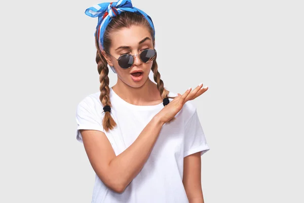 Bild av hipster ung kvinna bär rund spegel solglasögon och vit skjorta med hår flätor och blått pannband, vilket gör Swag gest och poserar över vit Studio bakgrund. Människor och känslo koncept — Stockfoto
