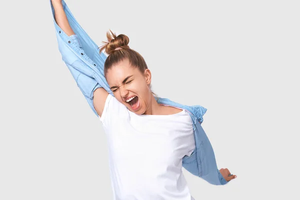 Glad blond ung kvinna som skriker med vidöppen mun, klädd i vit t-shirt och röd jacka, klädd i runda glasögon, isolerad över vit bakgrund. Människor och känslor koncept — Stockfoto