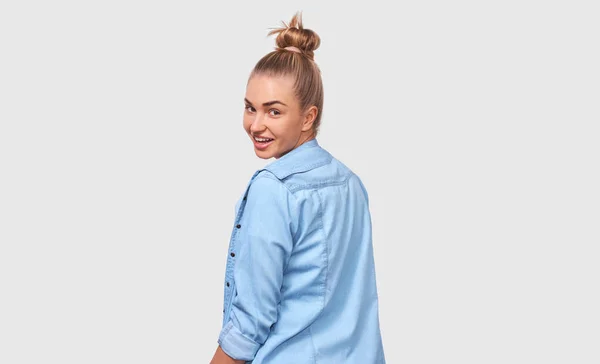 Visão traseira da bela jovem, sorrindo ampla e positivamente vestindo camisa casual azul e olhando para a câmera, isolada em fundo branco. Conceito de pessoas e emoções — Fotografia de Stock