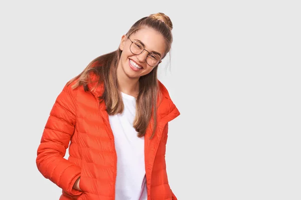 Studio portrait of happy blonde young woman smiling wide open mouth, dressing in white t-shirt and red jacket, wearing round eyewear, isolated over white background. People and emotions concept — Stock Photo, Image