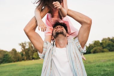 Neşeli baba görüntü açık havada onun küçük kızı ile vakit geçiriyor. Mutlu sevimli küçük kız gün batımı ışık sırasında parkta babası ile oynuyor. Babalar Günü. Baba ve çocuk sevgiyi paylaşıyor