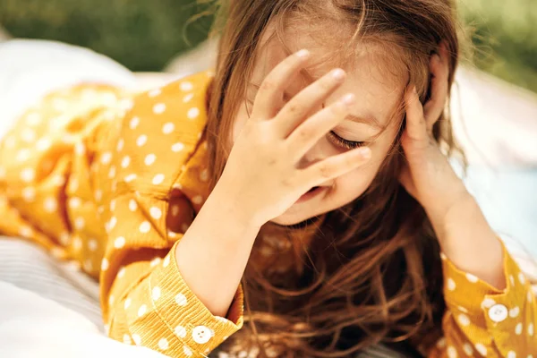 Closeup portrait of happy little girl smiling and lying on the blanket at grass, enjoying summertime outdoors. Adorable child having fun and relaxing during picnic with her family in the park. — Stock Photo, Image