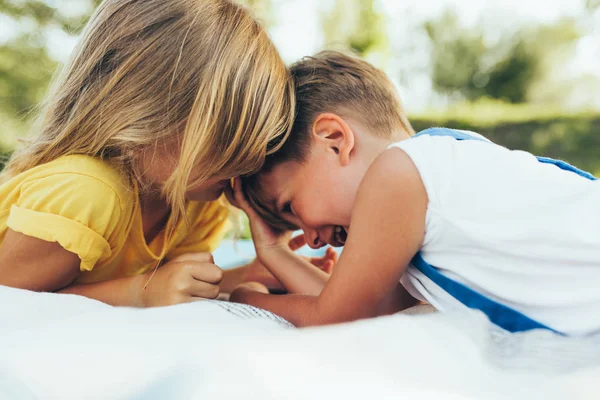 Portrait rapproché d'enfants heureux jouant sur la couverture à l'extérieur. Petit garçon et jolie petite fille souriant dans le parc. Adorables enfants qui s'amusent à la lumière du soleil. Soeur et frère passent du temps ensemble — Photo