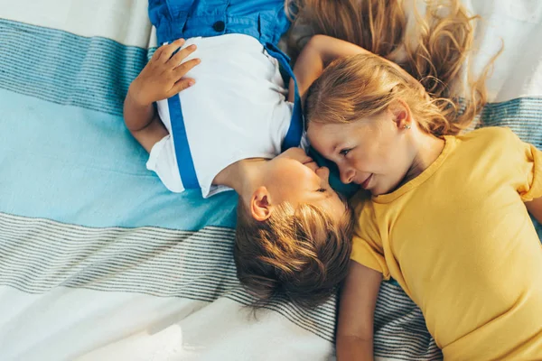 Horizontal top view of adorable children lying on the blanket, looking to each other. Happy little boy and little girl enjoying summertime in the park. Kids playing outdoors. Sister and brother — Stock Photo, Image