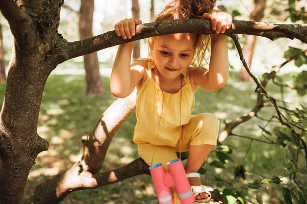 공원에서 여름철에 나무 의 브런치에 스윙, 노란색 장난 꾸러기를 입고 아이. 사랑스러운 금발의 어린 소녀는 자연 배경에서 재생됩니다. 햇빛에 숲에서 재미를 쾌활한 아이 — 스톡 사진