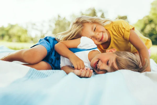 Счастливые дети играют на свежем воздухе. Веселый маленький мальчик и милая маленькая девочка улыбается и расслабляется в парке. Дети веселятся на солнце. Сестра и брат проводят время вместе . — стоковое фото