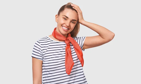 Encantadora jovem européia vestindo camiseta casual, cachecol vermelho no pescoço, sorrindo braodly e olhando para a câmera, isolado sobre fundo estúdio branco — Fotografia de Stock