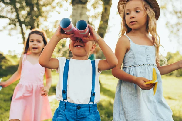 Bambini che giocano con un binocolo e un aereo di carta nella giornata estiva nel parco. Bambini felici che fanno finta di giocare a safari all'aperto nella foresta. Concetto di infanzia — Foto Stock