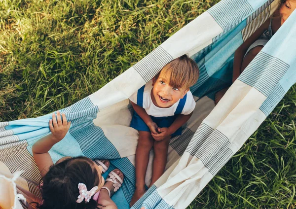 Bild von verspielten Kindern, die gemeinsam auf der Decke im grünen Gras spielen. glücklicher kleiner Junge und kleine Mädchen genießen den Sommertag im Park. fröhliche Kinder, die draußen spielen. Kindheit — Stockfoto