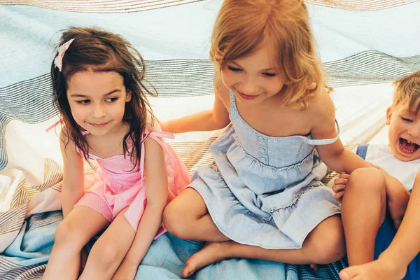 Niedlichen kleinen Mädchen und kleinen Jungen breit lächelnd und Spaß im Park. fröhliche Kinder, die auf der Decke sitzen und miteinander spielen. fröhliche Kinder, die draußen spielen — Stockfoto