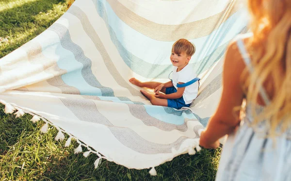 Bild vom kleinen Bruder und seiner Schwester, die mit der Decke auf grünem Gras spielen. fröhlicher kleiner Junge und kleines Mädchen, die Spaß haben und den Sommertag im Park genießen. fröhliche Kinder, die draußen spielen — Stockfoto