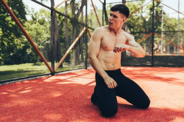 Yakışıklı fit erkek açık havada eğitim oturumu sonra bir dinlenme alarak. Sağlıklı atlet adam kaldırım spor yerinde oturan ve egzersiz egzersizleri sonra realxing. İnsanlar ve spor konsepti