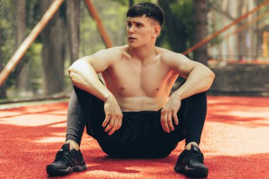Fit atlet adam açık havada eğitim oturumu sonra bir dinlenme alarak. Sağlıklı ve zinde adam oturma ve egzersiz egzersizleri sonra kaldırım spor yerinde rahatlatıcı. İnsanlar ve spor konsepti