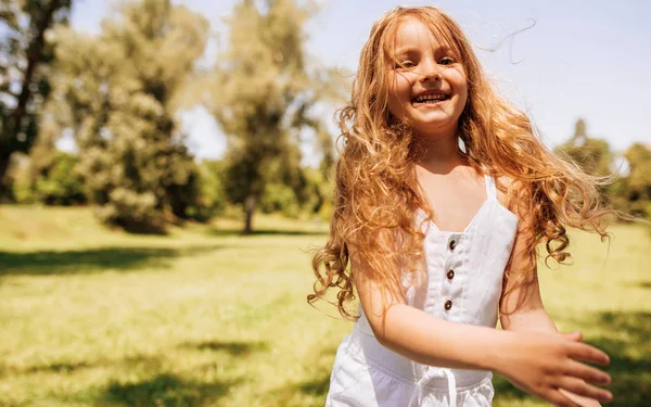 Portret szczęśliwej dziewczynki z długimi blond włosami grających na tle natury. Pozytywne dziecko korzystających letni dzień w parku. Wesoły dzieciak bawią się w lesie na słońcu. Szczęśliwego dzieciństwa — Zdjęcie stockowe