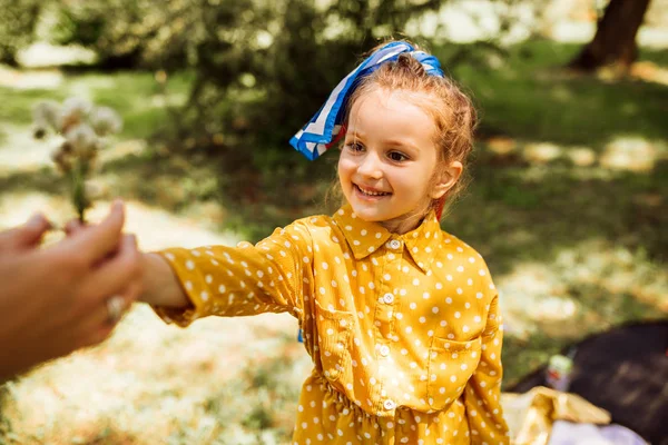 Im Freien Bild von entzückenden niedlichen kleinen Mädchen mit langen blonden Haaren, die Blumen an ihre Mutter in der Natur Hintergrund. fröhliches Kind spielt und genießt die Sommerzeit im Park. — Stockfoto