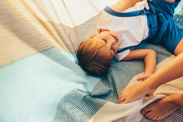 Above view of cute little boy lying on the blanket and playing with his sister outside. Happy child enjoying summer day in the park. Handsome kid smiling and having fun on sunlight outdoors. Childhood — Stock Photo, Image